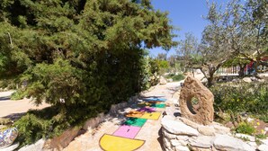A pathway with numbered stepping stones leading through a garden with trees and a stone structure. - Holiday Home 'Fattoria Spezia - Nespola' with Shared Pool, Garden and Shared Wi-Fi (Buseto Palizzolo)
