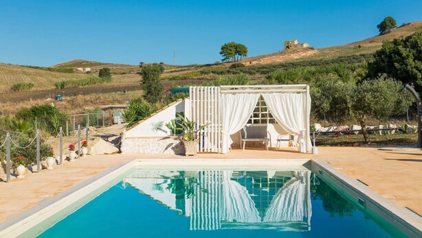 A pool area with a white gazebo, a stone wall, and a view of hills. - Holiday Home 'Fattoria Spezia - Limone' with Shared Pool, Shared Garden and Wi-Fi (Buseto Palizzolo)