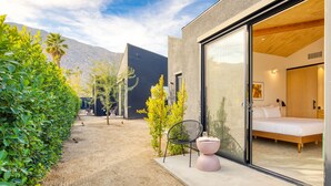 A modern building with a large glass door leading to a bedroom with a bed and a nightstand. - Blackhaus A1 by AvantStay | Modern Room + Pool (Palm Springs)