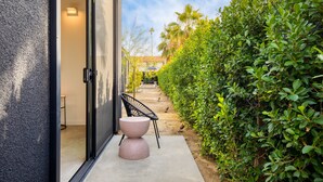 A modern building with a glass door, a concrete bench, and a well-maintained hedge.