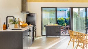 A modern kitchen with a large island, dark cabinetry, and a view of a patio area with outdoor furniture.