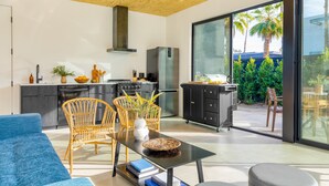 Una cocina moderna con comedor, ventanas amplias y vistas a palmeras.