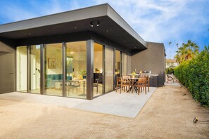 A modern house with a large glass patio, a dining area, and a well-maintained garden. - Blackhaus D Suite by AvantStay | Modern Spaces (Palm Springs)