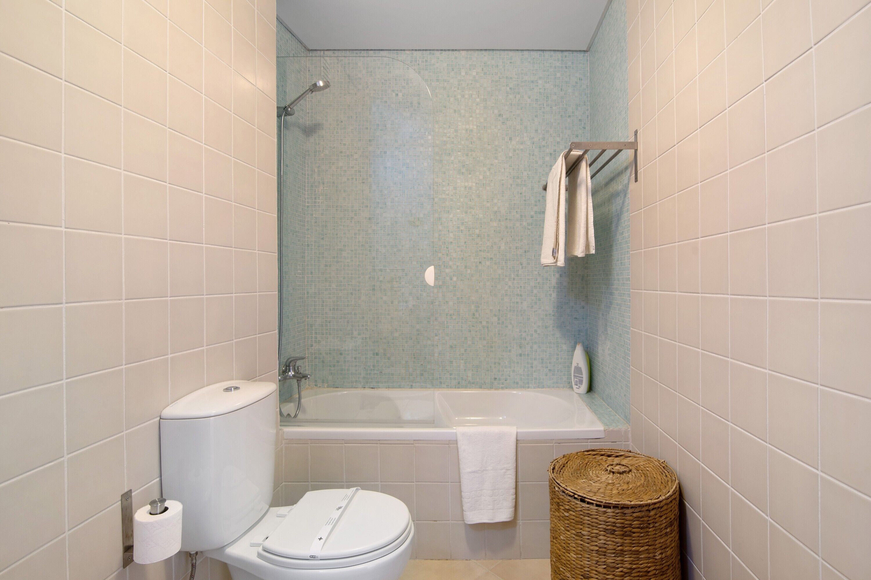 A bathroom with a toilet, a shower, a bathtub, and a towel rack.