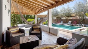 A covered patio with wicker furniture, a hammock, and a pool in the background. - Holiday Home 'Holi' with Private Pool, Wi-Fi and Air Conditioning (Valada)
