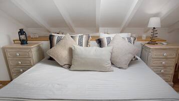 A bedroom with a large bed, two bedside tables, a lamp, and a lantern.