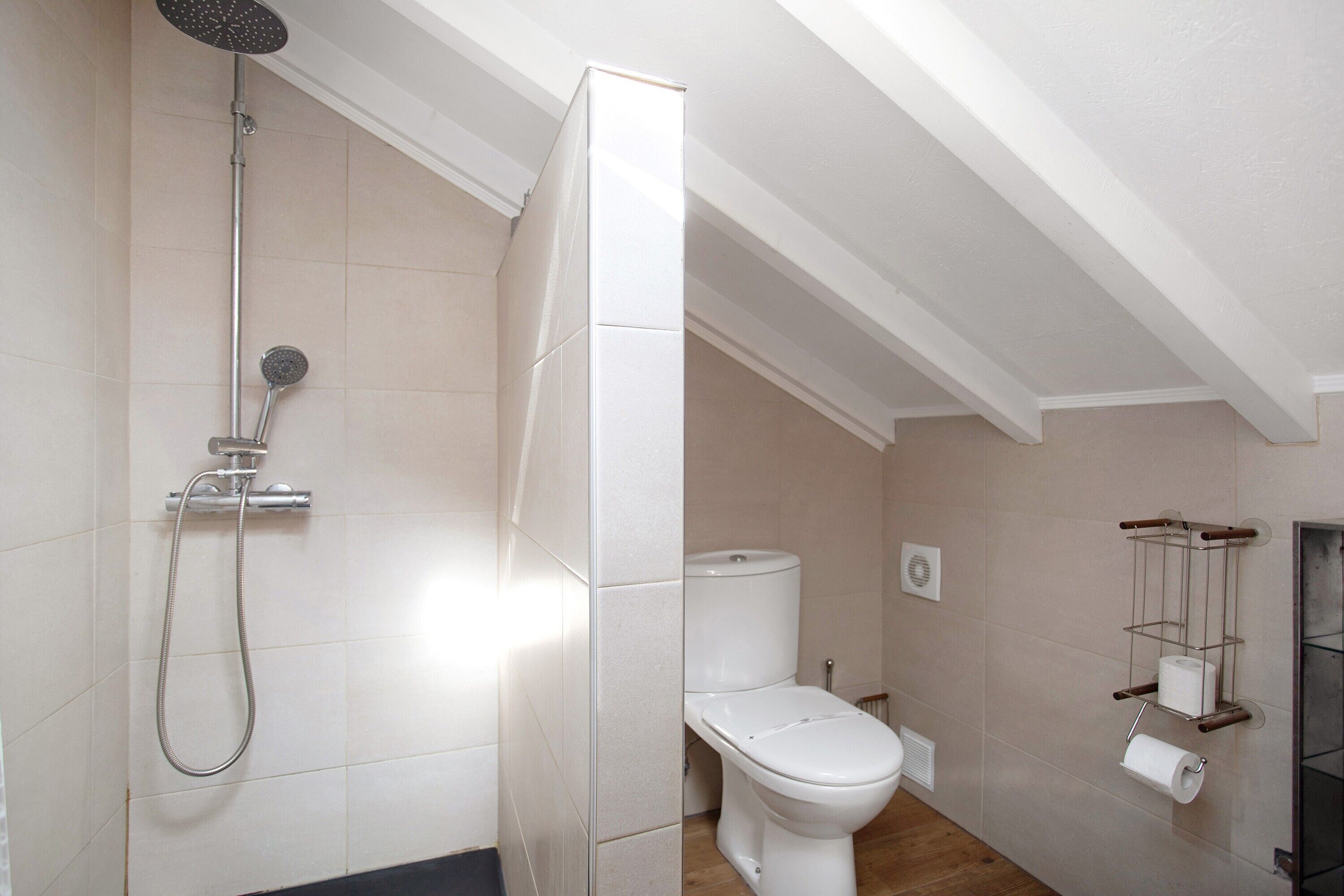 Une salle de bain équipée d’une douche, de toilettes et d’un porte-rouleau de papier toilette.