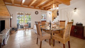 A dining area with a wooden ceiling, wicker chairs, a glass table, and a fireplace. - Holiday Home 'Holi' with Private Pool, Wi-Fi and Air Conditioning (Valada)