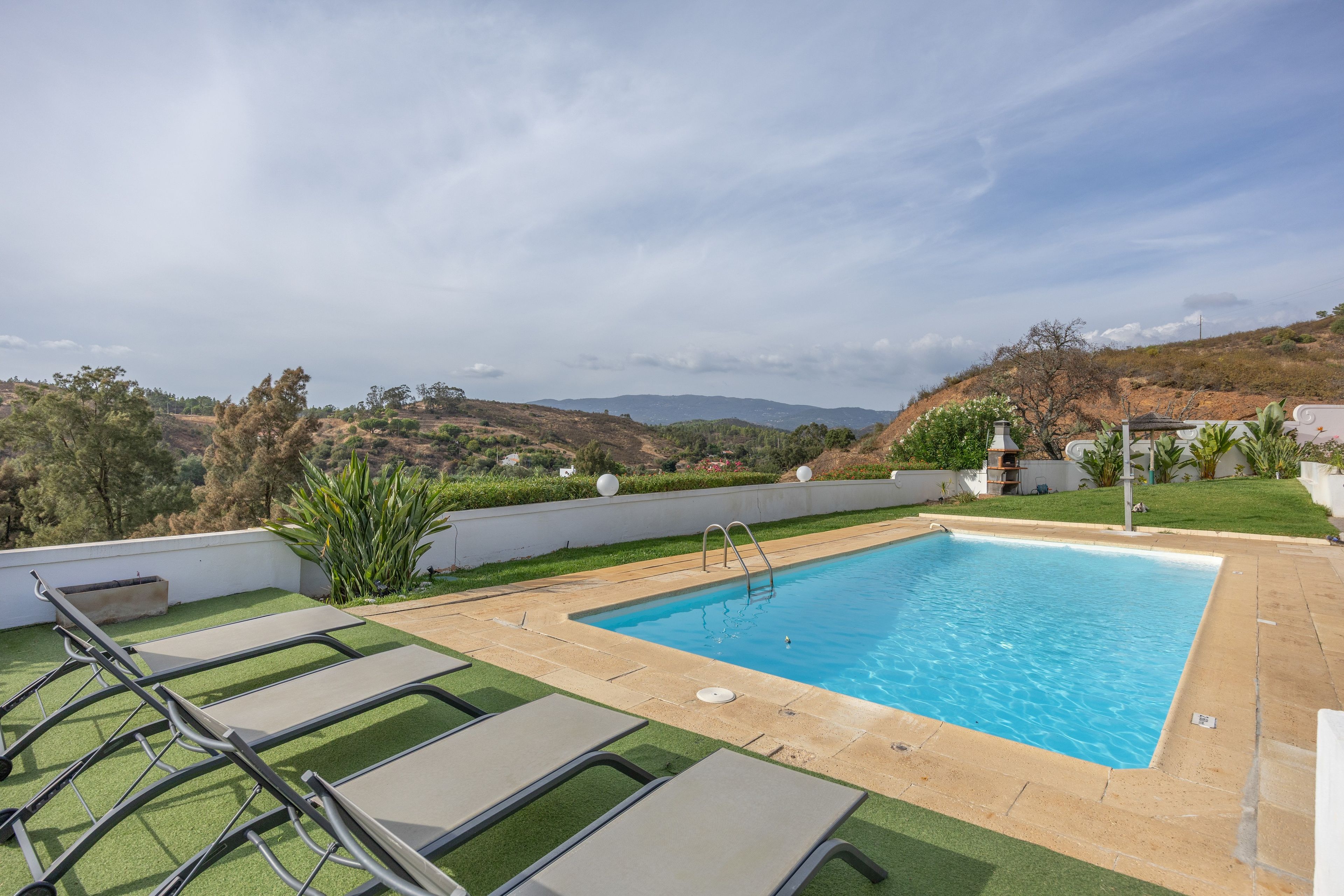 A swimming pool with a view of hills and a white wall.