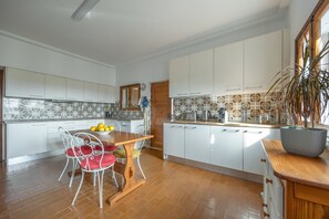 A modern kitchen with white cabinets, a wooden dining table, and a potted plant. - Villa with Private Pool and Terraces – Perfect Holiday in Portimão (Portimão)