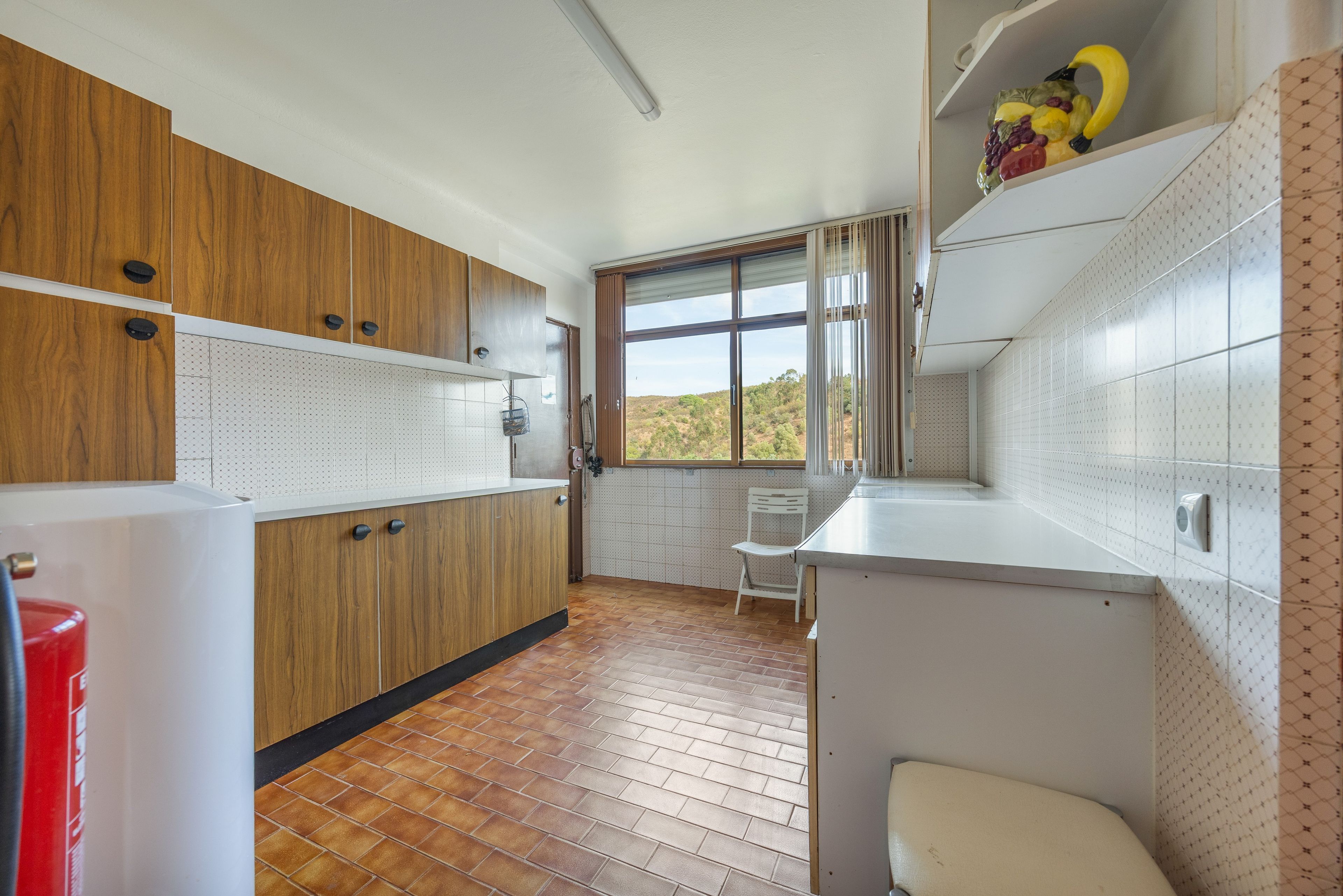 Una cucina con mobili in legno, un piano di lavoro bianco e una finestra vista all'esterno.