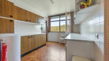 Una cucina con mobili in legno, un piano di lavoro bianco e una finestra vista all'esterno.