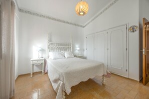 A bedroom with a bed, nightstands, a wardrobe, and a door.