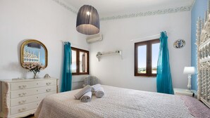 Un dormitorio con cama, cómoda, espejo, ventana y cortinas.