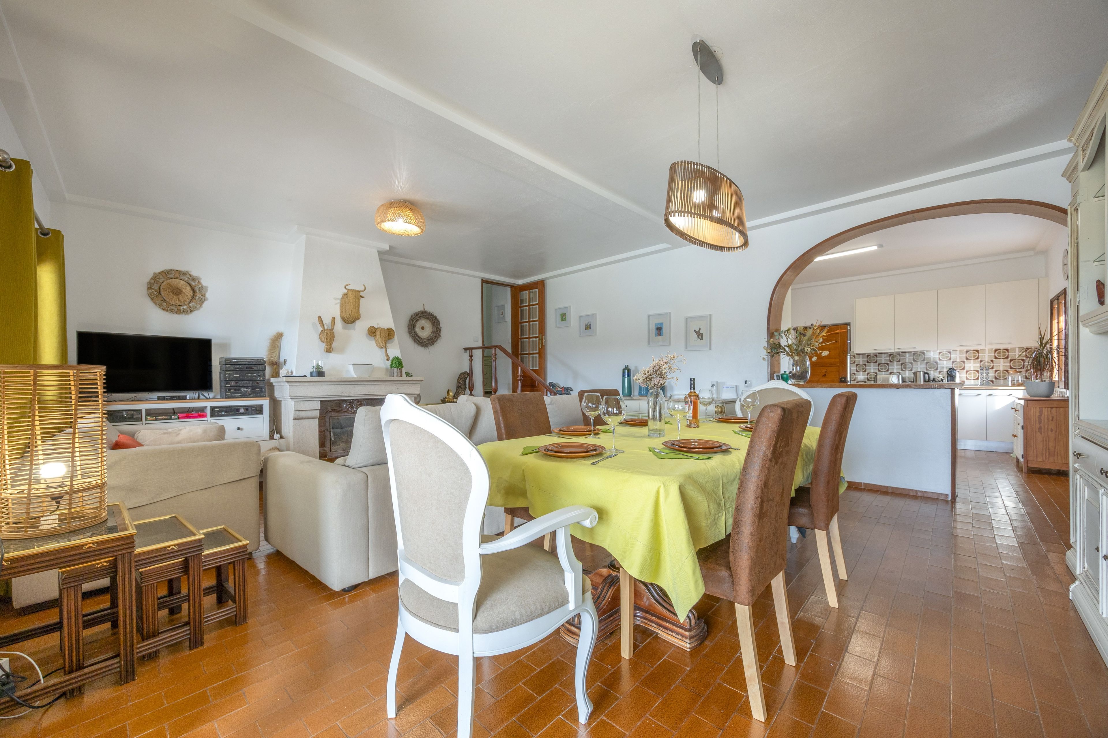 A spacious living area with a dining table set for four, a fireplace, and a television in the background.
