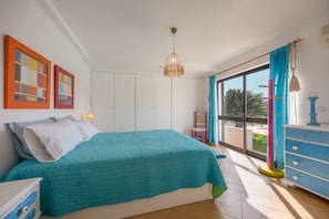 A bedroom with a bed, wardrobe, and a view of the outdoors.