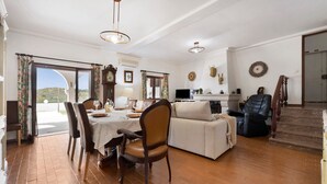 Un comedor con una mesa dispuesta para cuatro personas, un sofá y un televisor al fondo.
