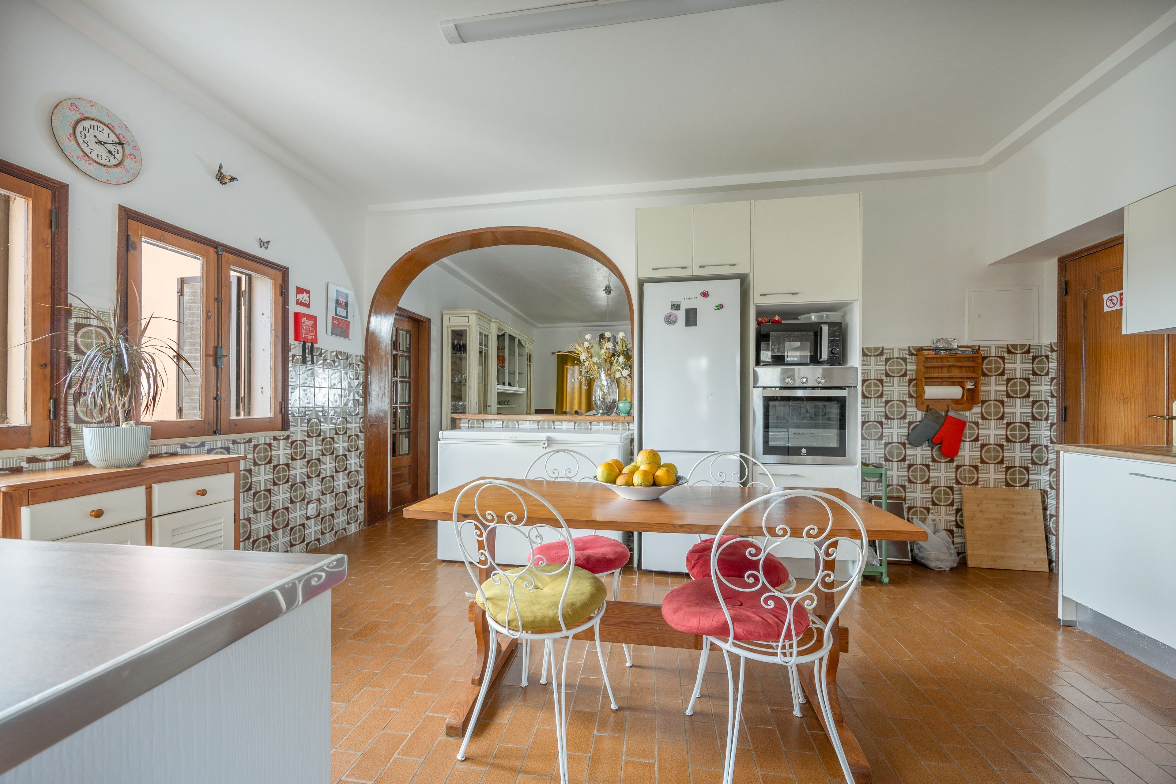 A kitchen with a wooden table, chairs, a refrigerator, and a microwave.