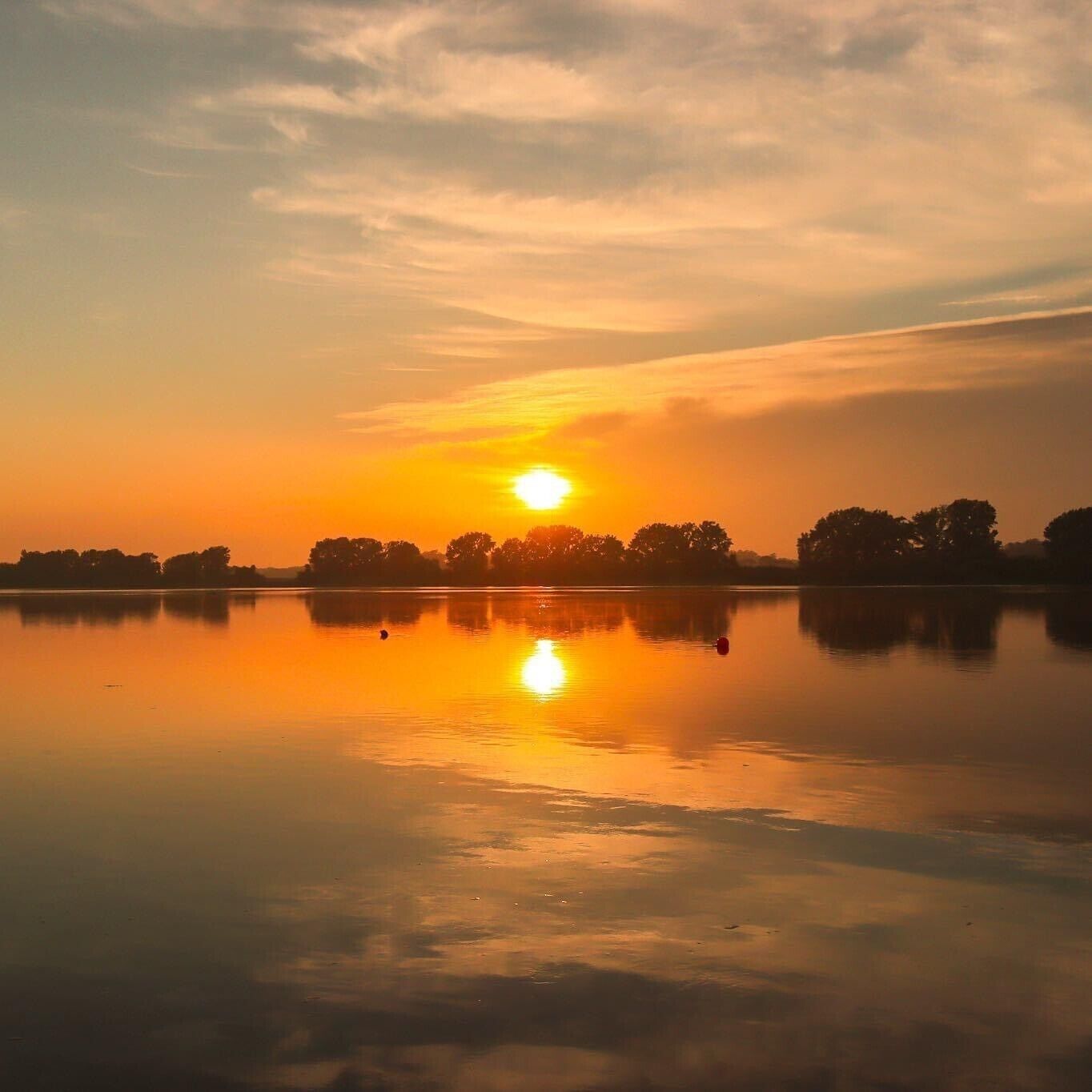 Ruhige Wasserfläche spiegelt den Sonnenuntergang.