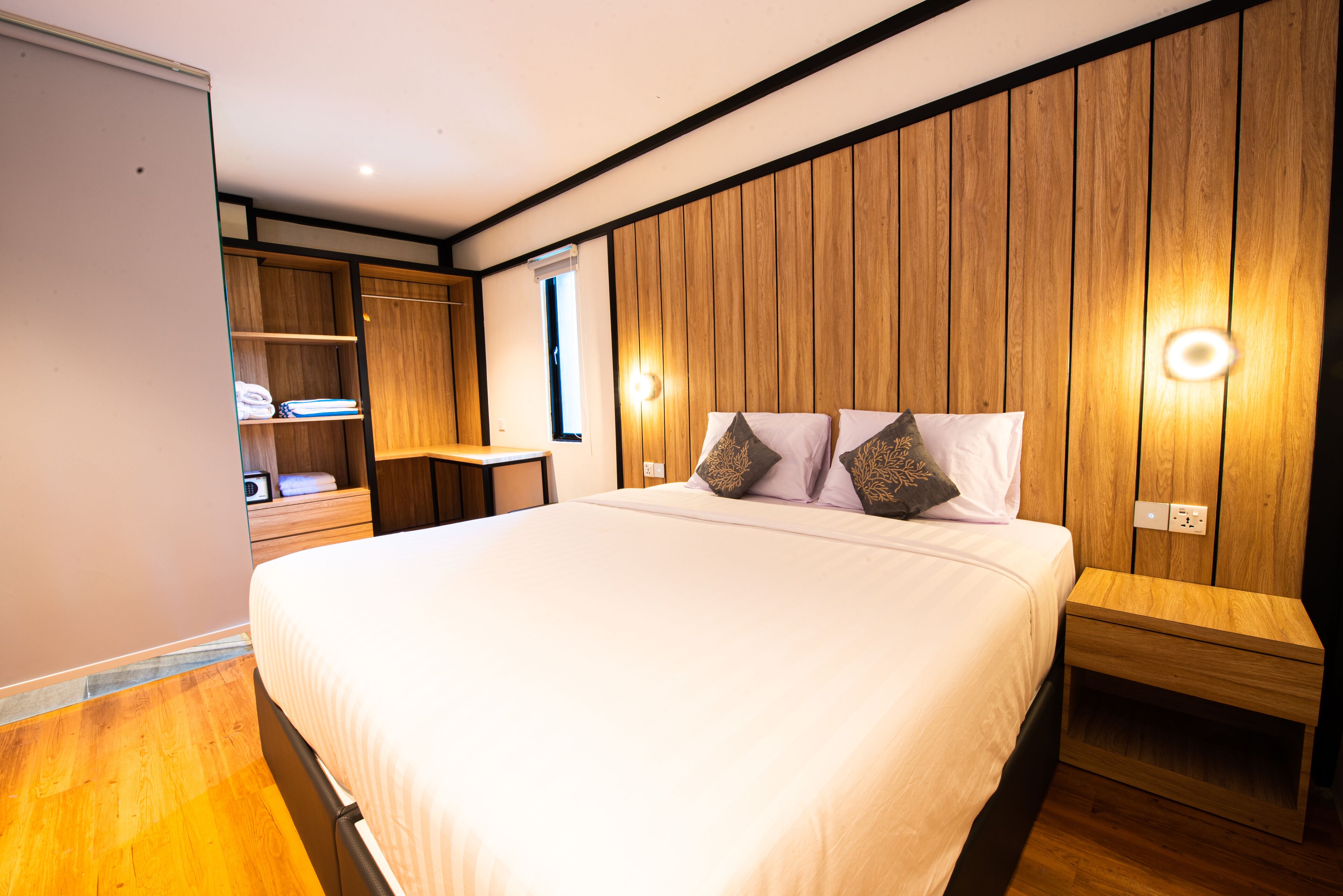 A bedroom with a large bed, wooden panel walls, a nightstand, and a wardrobe.
