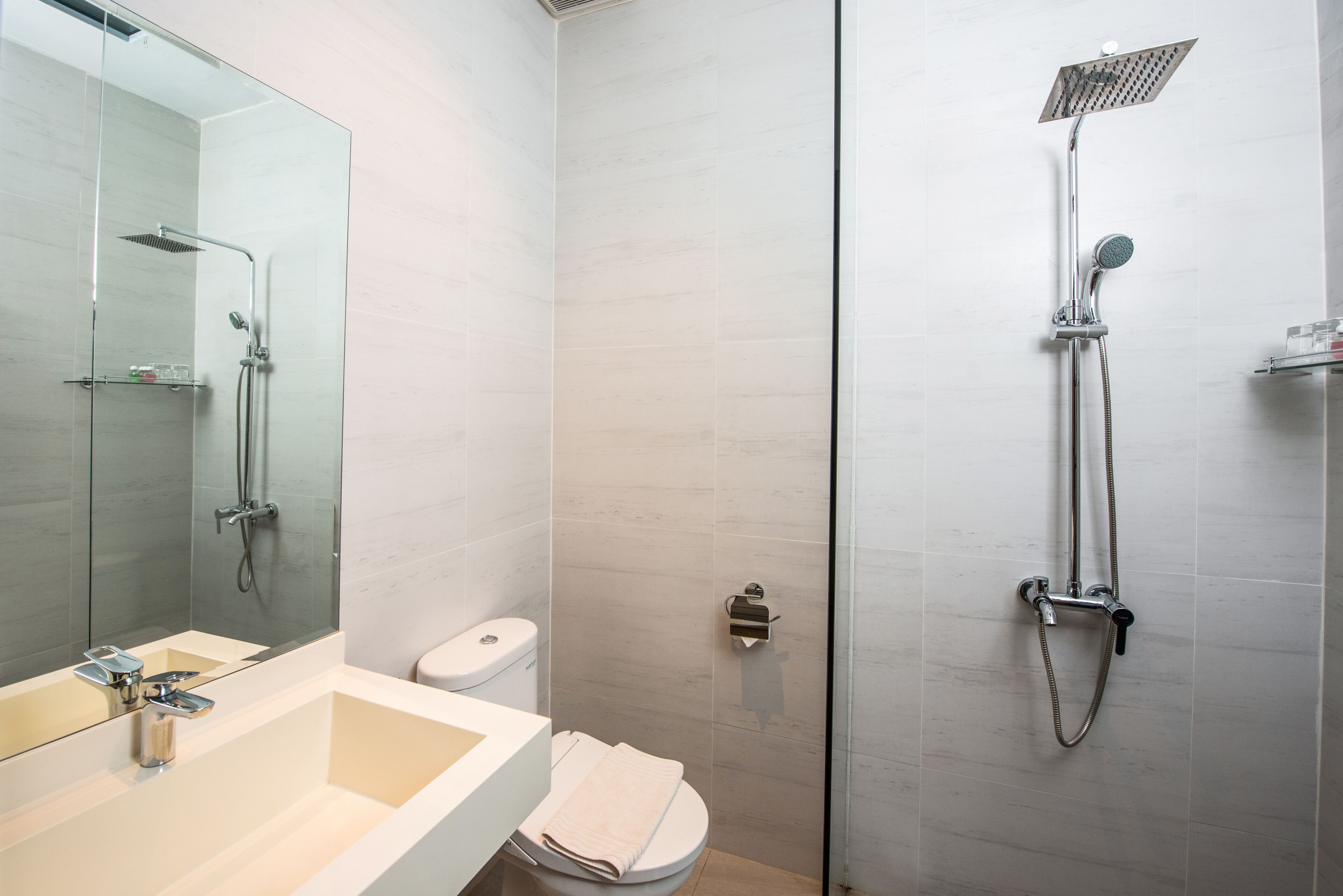 Ein modernes Badezimmer mit einer Glaskabine, einem weißen Waschbecken und einer Toilette.