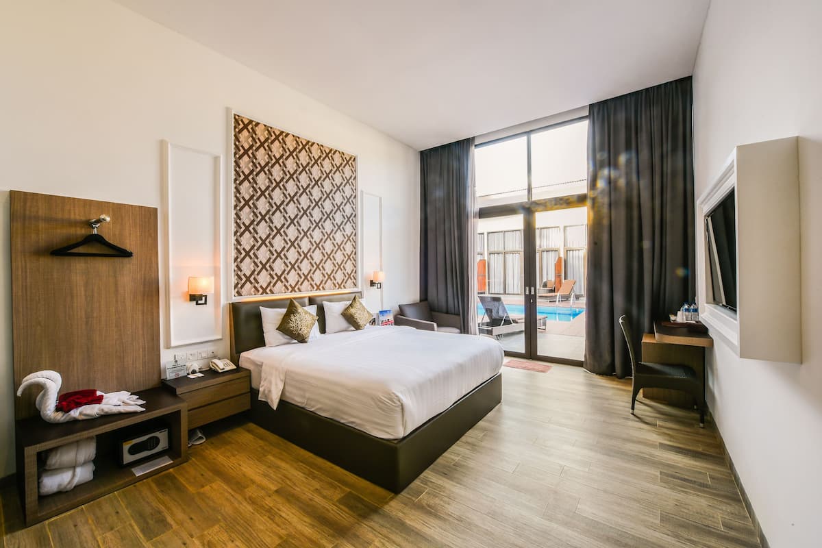 Ett modernt hotellrum med en stor säng, ett skrivbord, en TV och utsikt över poolen.