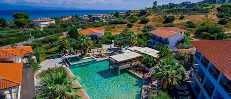 A resort with a swimming pool, palm trees, and a view of the sea.