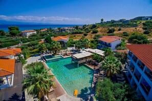 A resort with a swimming pool, palm trees, and a view of the sea. - Flegra Palace Hotel & Spa (Kassandra)