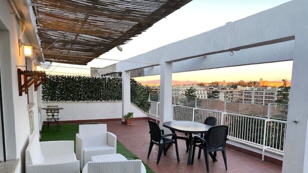 Una terraza en la azotea con mobiliario exterior, vistas panorámicas de la ciudad y una pérgola.