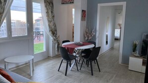 Un comedor con una mesa y sillas, una mesita blanca y vistas al exterior.