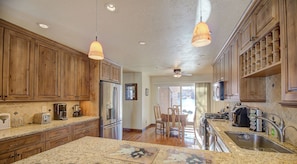 A kitchen with wooden cabinets, granite countertops, and a dining area with chairs.