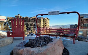 A red bench and chair in a snowy outdoor area with a view of buildings in the background.