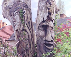 Tree carvings adorn the garden, featuring intricately carved human faces.