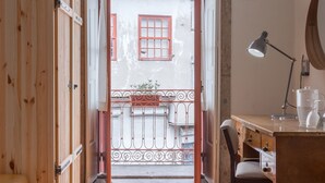 A wooden door leading to a balcony with a metal railing and a small plant. - The Poets Inn (Porto)