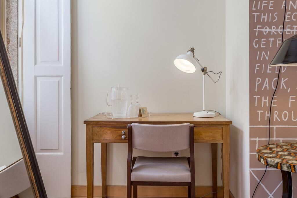 Una scrivania in legno con una sedia, una lampada da tavolo e un vaso di vetro.