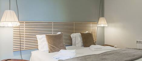 A neatly made bed with a headboard, two bedside lamps, and a bedside table with a lamp.