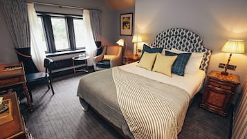 Un dormitorio ordenado con una cama grande, una silla, un escritorio y una ventana con cortinas.
