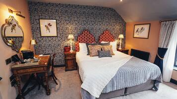 A bedroom with a large bed, a desk with a chair, a dresser, and a mirror.