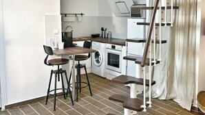 A compact kitchen with a washing machine, a small dining area with stools, and a staircase. - ⭐️⭐️🇫🇷PARIS/BORGET✈️CDG/VILLEPINTE/ASTERIX/STADE DE FRANCE/DISNEYLAND🇫🇷⭐️⭐️ (Garges-lès-Gonesse)