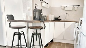 A modern kitchen with white cabinets, two bar stools, a coffee machine, and a sink. - ⭐️⭐️🇫🇷PARIS/BORGET✈️CDG/VILLEPINTE/ASTERIX/STADE DE FRANCE/DISNEYLAND🇫🇷⭐️⭐️ (Garges-lès-Gonesse)