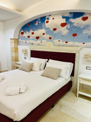 Ein Hotelzimmer mit einem großen Bett, einer Kopfteil mit dekorativem Design und einem Wandbild von Wolken und Heißluftballons.