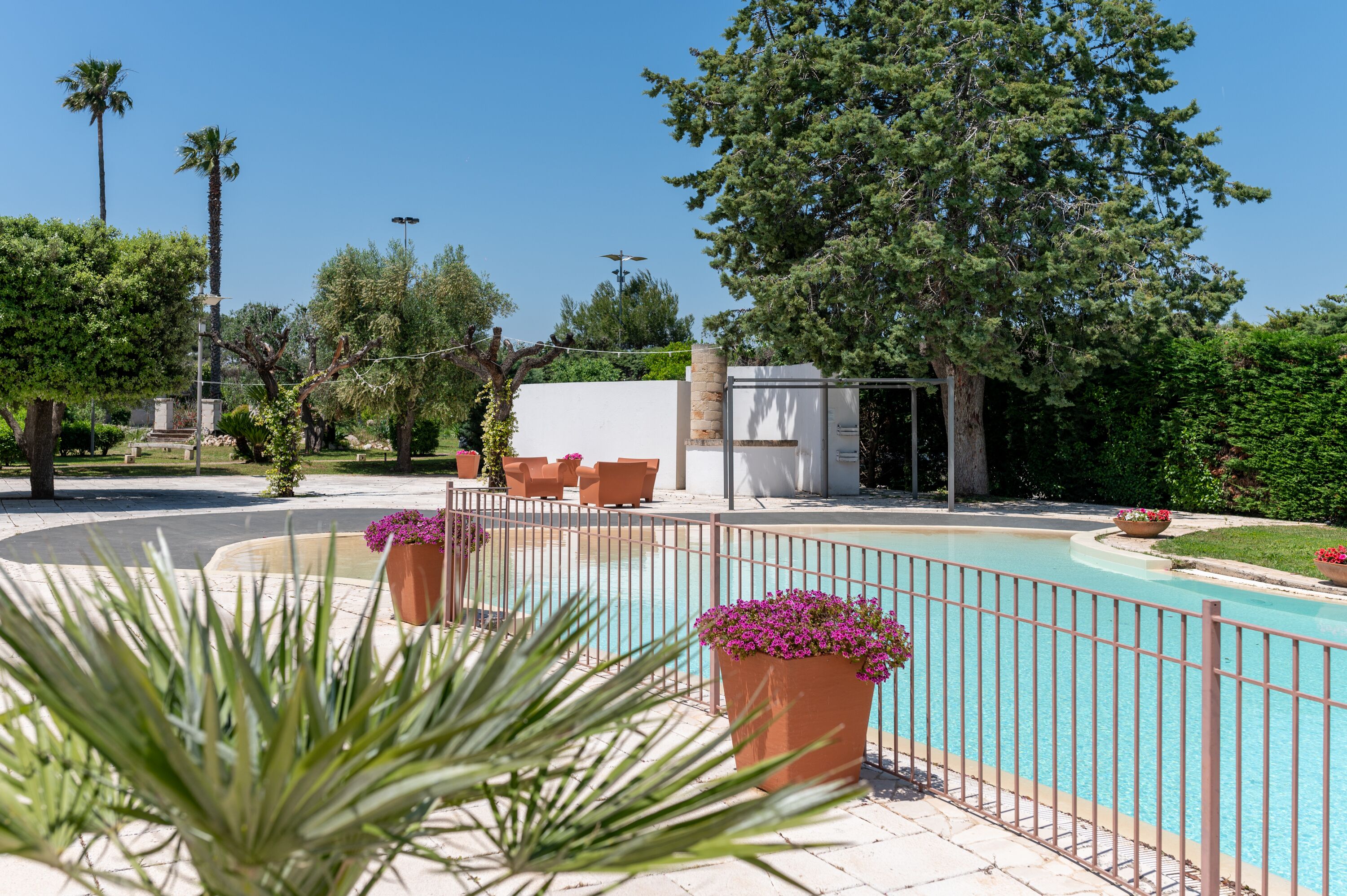 A pool area with a fence, potted plants, and outdoor seating.