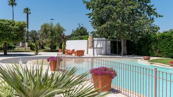 A pool area with a fence, potted plants, and outdoor seating.