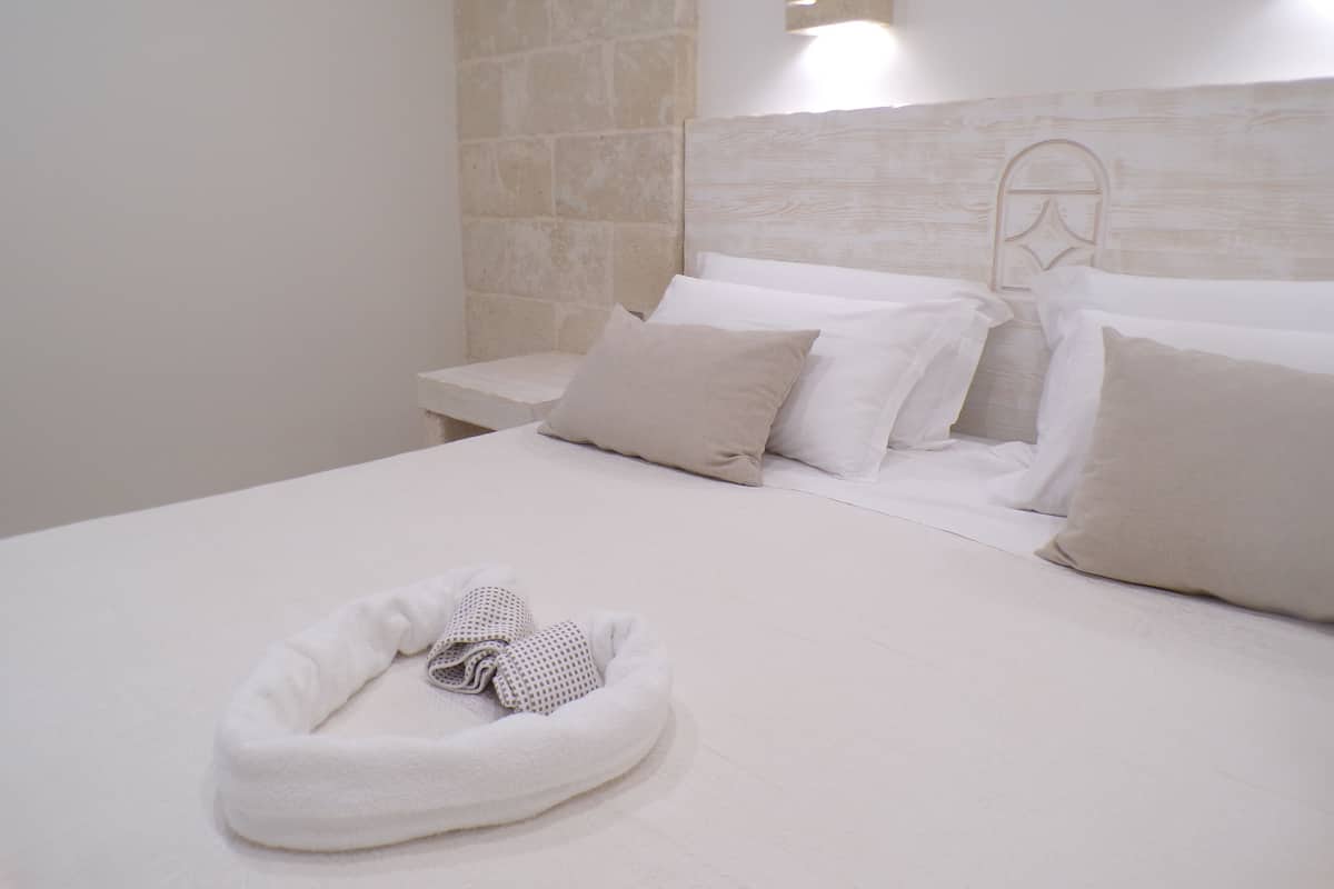A neatly made bed with white linens and a towel in a headboard.