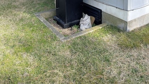 A portable grill unit placed on a grassy area in front of a house with light gray siding.