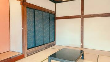 A traditional Japanese room with tatami flooring, a low table, sliding doors, and a ceiling light fixture.