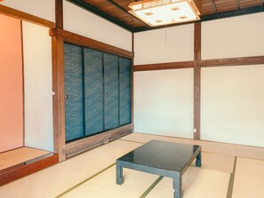 A traditional Japanese room with tatami flooring, a low table, sliding doors, and a ceiling light fixture. - Kominka guest house YUINOYA (Nakanoto)