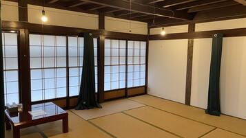 A traditional tatami mat room with sliding doors, a wooden table, and hanging light fixtures.