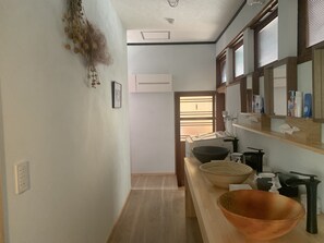 A modern bathroom with a wooden vanity, a large bowl sink, and a mirror above the counter. - Kominka guest house YUINOYA (Nakanoto)