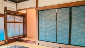 A traditional Japanese room with tatami flooring, a sliding door with a blue pattern, and a black table.